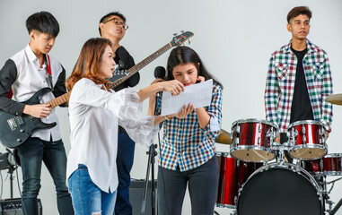 Group shot of teenage musicians playing the music and singing a song together. Young students play...