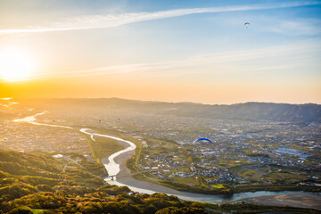 和歌山県紀の川市の百合山上空から見える夕日をパラグライダーから空撮。秋、11月。 - obrazy, fototapety, plakaty
