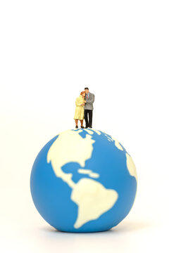 Couple and Global concept. Two businessman and businesswoman miniature figure people walking and standing on mini world ball on white background.