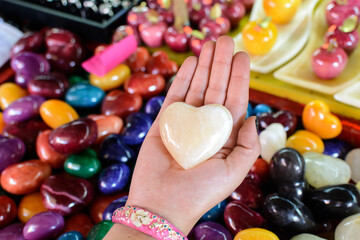 Persona sosteniendo un corazon de piedra natural. Corazon tallado en piedra preciosa.