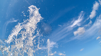高速シャッターで撮影した夏の青空と公園の噴水の水滴の様子