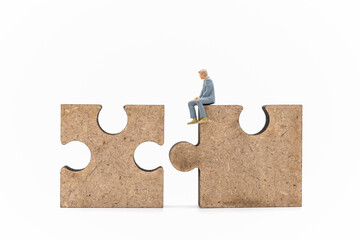 Business, Planning and Solution Concept. Businessman miniature figure people sitting on wooden jigsaw puzzle on white background.