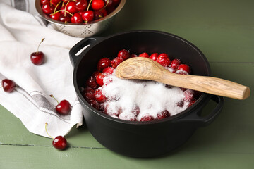 Preparing of sweet cherry jam on color wooden background
