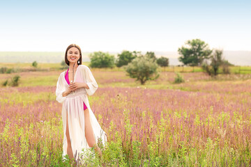 Fototapeta na wymiar Beautiful young woman relaxing in blooming field