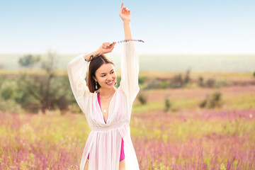 Beautiful young woman relaxing in blooming field