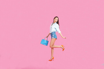 Happy girl holding a shopping bag on a pink background,Online shopping