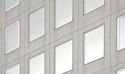 modern concrete building facade with array of clean rectangle reflective windows abstract...