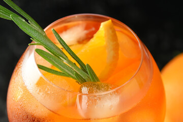 Glass of tasty aperol spritz cocktail on dark background, closeup