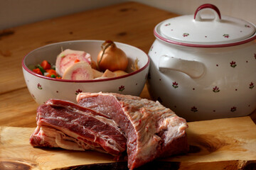 Rindfleisch vom Brustkern auf Zirbenholzbrett mit Suppenterrine, Suppengemüse und Suppenknochen 