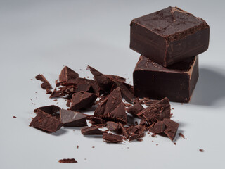 Broken pieces of chocolate and cocoa powder on a white background