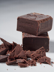 Broken pieces of chocolate and cocoa powder on a white background