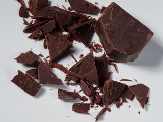 Broken pieces of chocolate and cocoa powder on a white background