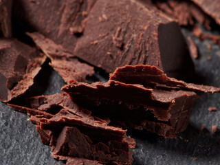 Broken pieces of chocolate and cocoa powder on a black background