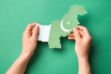 Female hands with flag map of Pakistan on color background