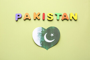 Flag of Pakistan in shape of heart on color background