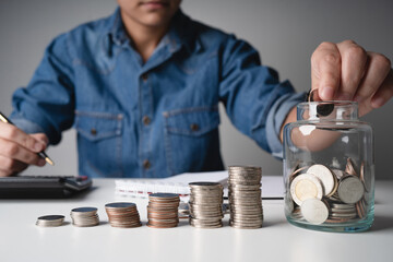 Businessman saving money with putting coins in glass, finance accounting concept.