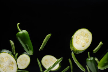 Flying green vegetables on dark background