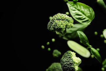 Fototapeta Flying green vegetables on dark background obraz