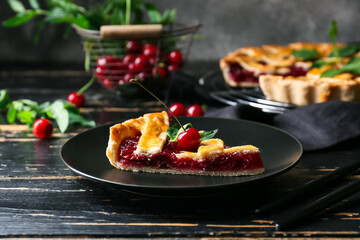 Plate with piece of tasty cherry pie on dark wooden table, closeup