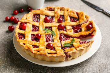 Plate with tasty cherry pie on grunge background, closeup