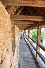 Fototapeta premium Rothenbauer Stadtmauer - Junge Frau läuft durch den Laubengang Stadtmauer Rothenburg ob der Tauber, Sommer, Franken, Bayern, Deutschland