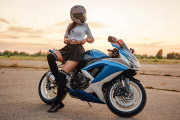 Obraz na płótnie Canvas Female motorcyclist and modern motorbike on country road