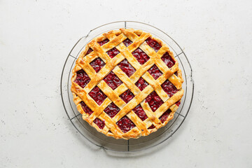 Grid with tasty cherry pie on light background
