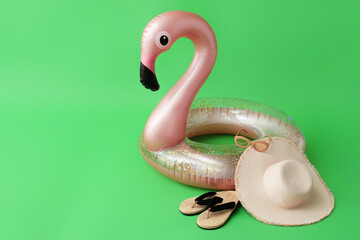 Inflatable ring, hat and flip-flops on color background