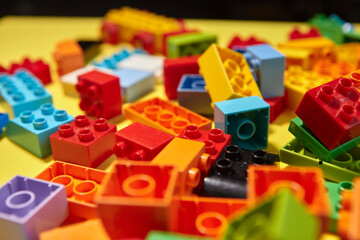 Colored toy bricks with Toy colorful letters on yellow background. Educational toy for children.