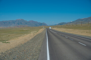 Van drives along an empty highway passing through the steppe towards the mountains, Altai photo