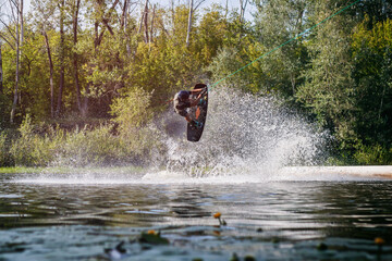 Man makes an extreme jump on wakeboarding with splashes of water.