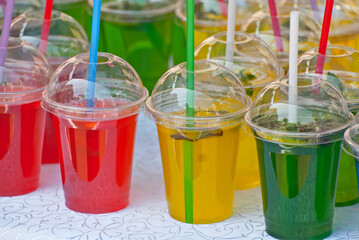 Multicolored fruit drinks close-up. Non-alcoholic drinks in plastic cups at the festival. Cocktails with juice and greens.