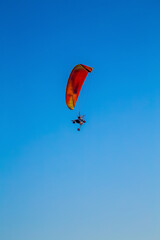 paraglider flying with paramotor on air on evening against the blue sky