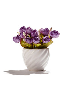 Subject shot of violet tulips in little white ceramic pot. Fine faux flowers for interior design are isolated on the white background. 
