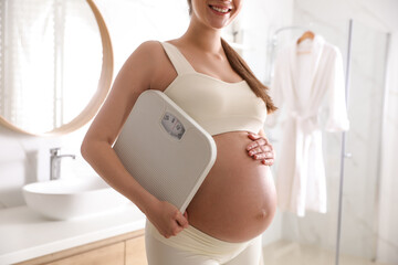 Young pregnant woman with scales in bathroom, closeup