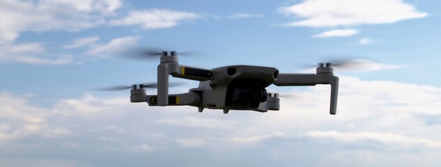 A drone in flight against a background of blue sky and white clouds.