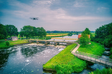 Water swirls from the weir in the river Vecht in the Netherlands. Fish passage, fish ladder to the right of the water, Overijsselse Vecht, A flying drone in the blue sky