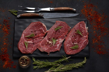 Three pieces of traditional thin steak cut from the tenderloin on wooden cutting board with olive...