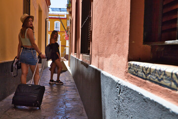 Two beautiful young women walking down a narrow street in a European city. The women are carrying...