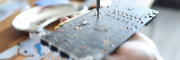 Master disassembling video card with screwdriver closeup