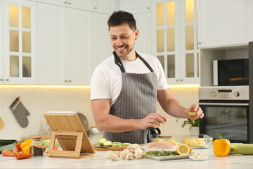 Man making dinner while watching online cooking course via tablet in kitchen