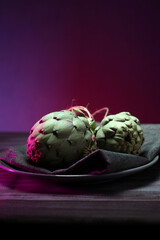 still life photo of artichokes in dark food photography style with colored lights