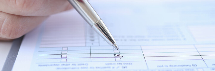 Woman putting mark with ballpoint pen on questionnaire closeup