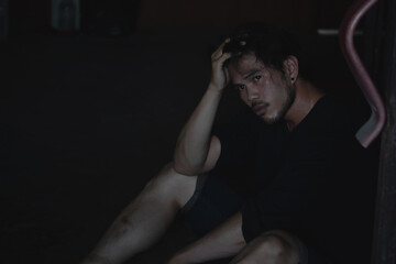 Depressed and hopeless asian man sitting alone after using drugs sitting on the floor. Drugs addiction and withdrawal symptoms concept.