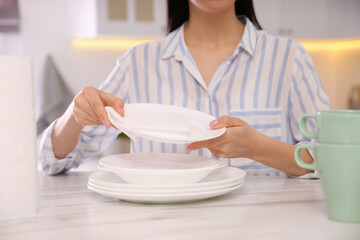Woman wiping plate with paper towel in kitchen, closeup