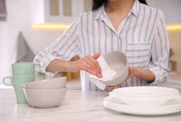 Woman wiping bowl with paper towel in kitchen, closeup