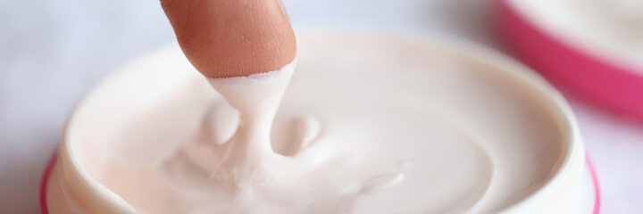 Man taking out nourishing cream from jar closeup