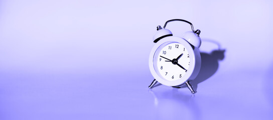 Small alarm clock on a blue background. Side view, place for text.
