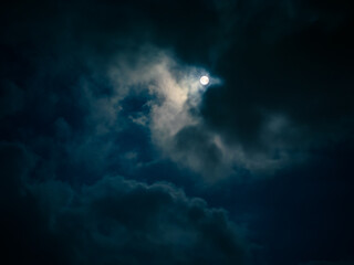 Naklejka na ściany i meble Full moon among clouds in the night sky.