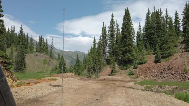 POV while driving a off road vehicle on a wide portion of Alpine Loop trail through the San Juan mountains near Silverton Colorado; creek runs across trail; concepts of off roading and adventure